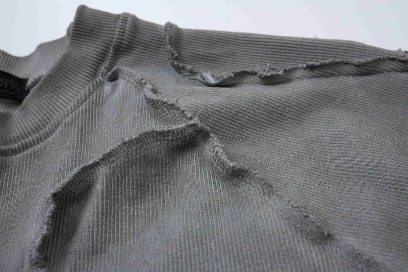 Close-up of a gray ribbed compression tee with raw frayed seams and deconstructed streetwear detailing