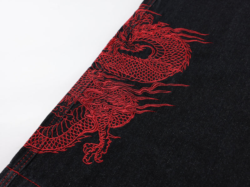 Close-up of red dragon embroidery on black denim pant leg