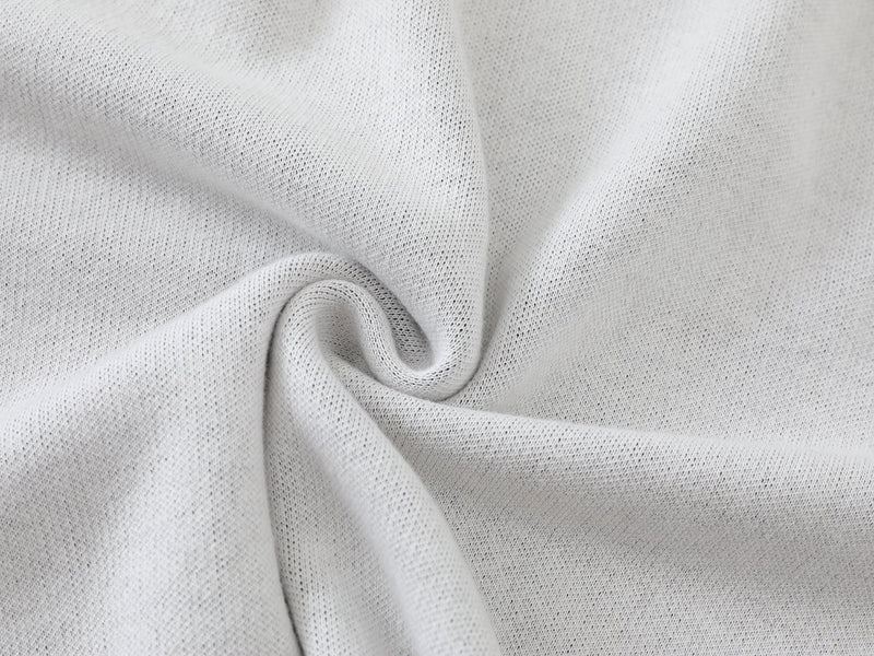 Close-up of white knit fabric gathered in a swirl, showing soft textured knit