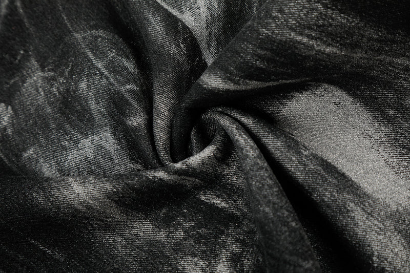 Extreme close-up of black denim fabric with painted wash texture and soft folds