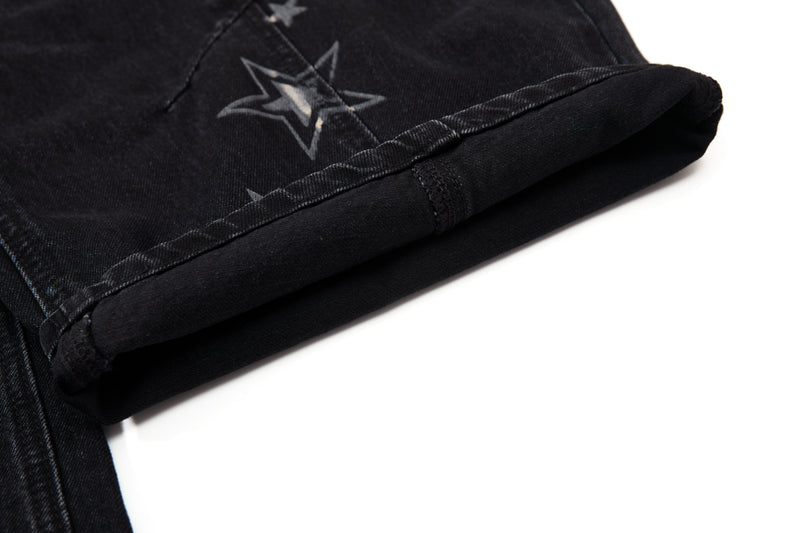 Close-up of folded black denim cuff with star print and hem stitching