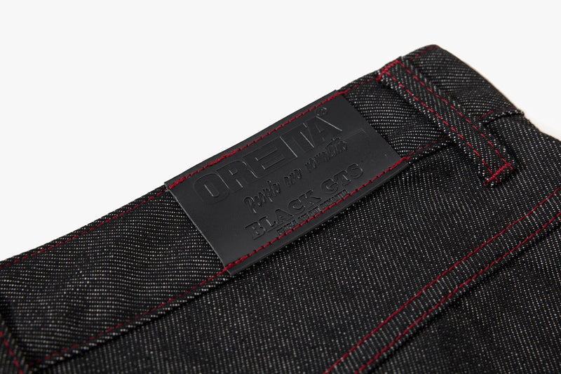 Close-up of black waistband patch labeled OREVA with red contrast stitching