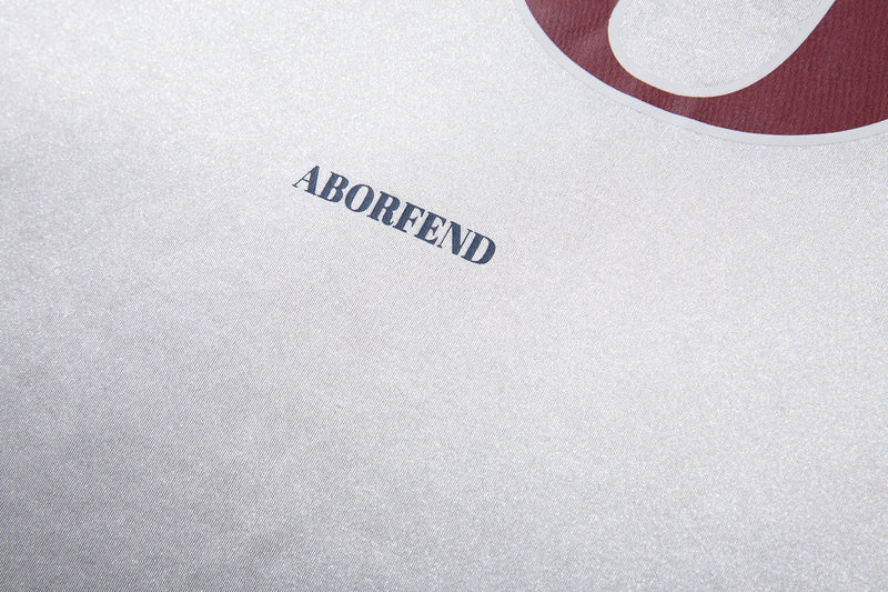 Close-up of white jersey tee with ABORFEND text near lower chest