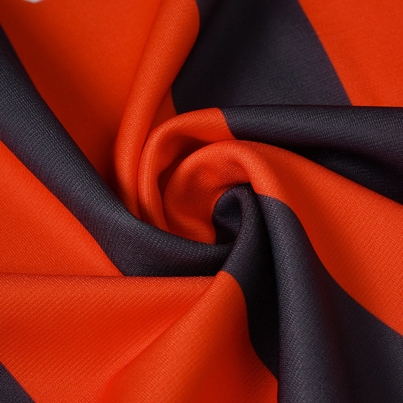 Close-up of orange and black striped performance jersey fabric with a smooth, textured sportswear finish