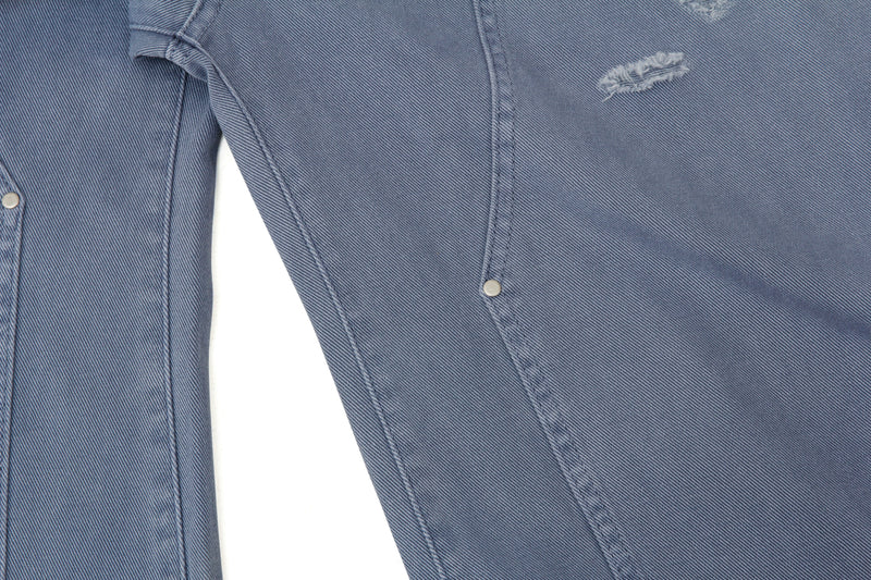 Close-up of the side seam and pocket area on blue distressed denim jeans