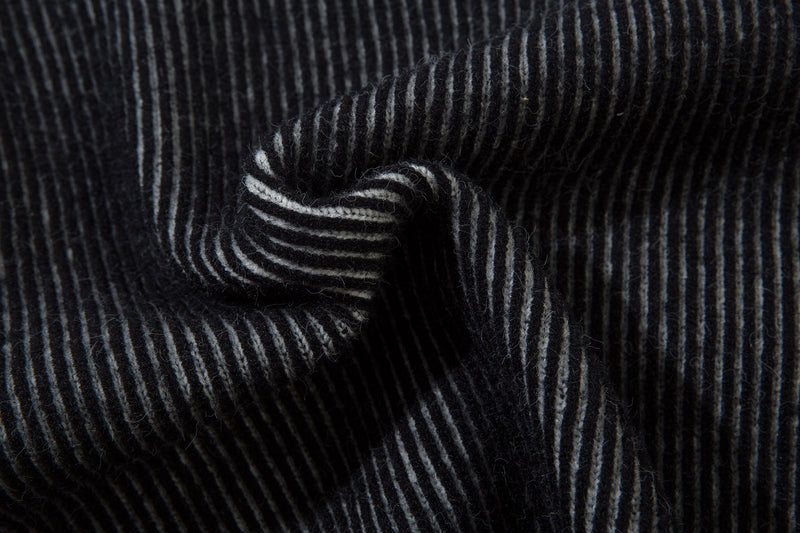 Close-up of folded black ribbed knit sleeve cuff with gray stripes