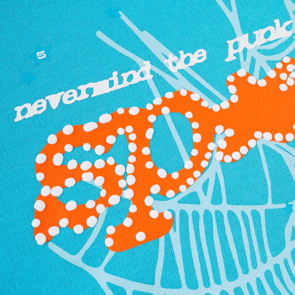 Close-up of the Sp5der “Nevermind the Spider” Hoodie in sky blue 440GSM heavyweight cotton, featuring stylized white and orange text with a polka-dot SPOT and abstract lines—ideal streetwear inspiration.