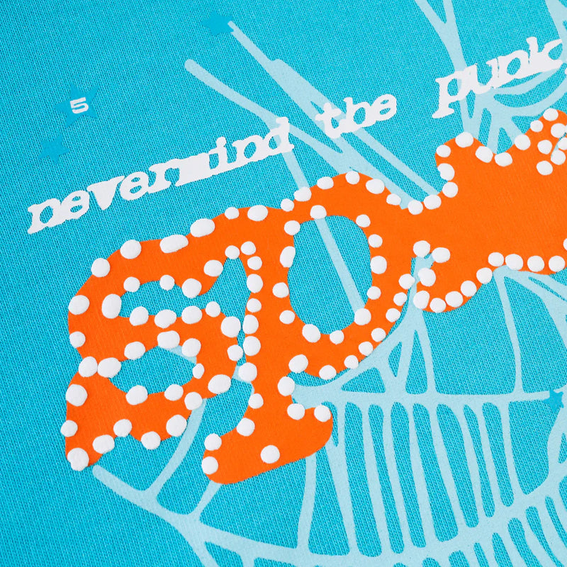 Close-up of the Sp5der “Nevermind the Spider” Hoodie in sky blue 440GSM heavyweight cotton, featuring stylized white and orange text with a polka-dot SPOT and abstract lines—ideal streetwear inspiration.
