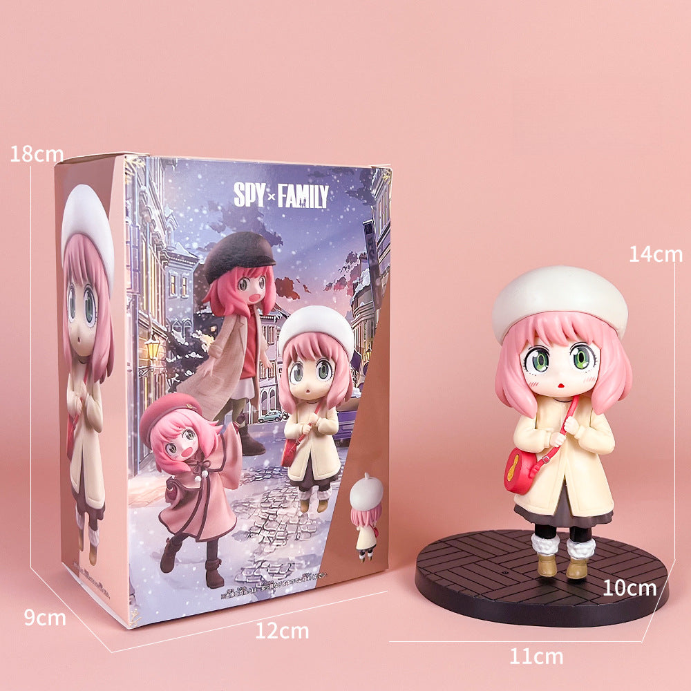 The Spy x Family Detective Anya PVC Figure Set features a 14 cm character with pink hair and green eyes, dressed in a white hat and coat. It stands beside its movie version box with a winter scene.