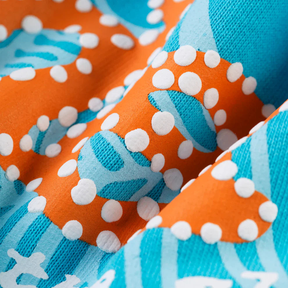 Close-up of colorful fabric with white polka dots, abstract shapes, and wavy lines—ideal for the Sp5der “Nevermind the Spider” Hoodie in Sky Blue, a 440GSM heavyweight streetwear pullover made from premium cotton fleece. Rich texture, artfully folded.