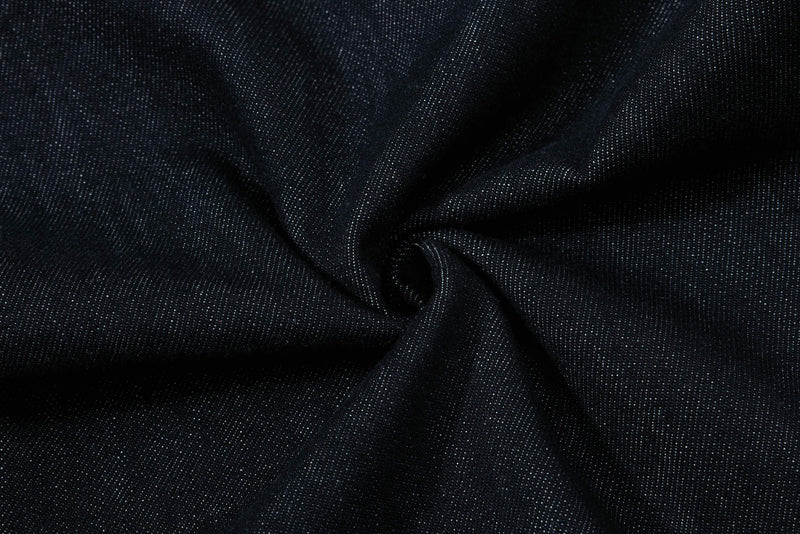 Close-up of dark wash denim fabric with soft folds and textured weave