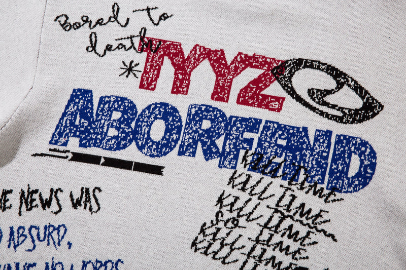 Close-up of red and blue graffiti embroidery on white knit sweater front