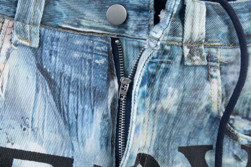Close-up of front zipper fly and button on blue printed denim pants