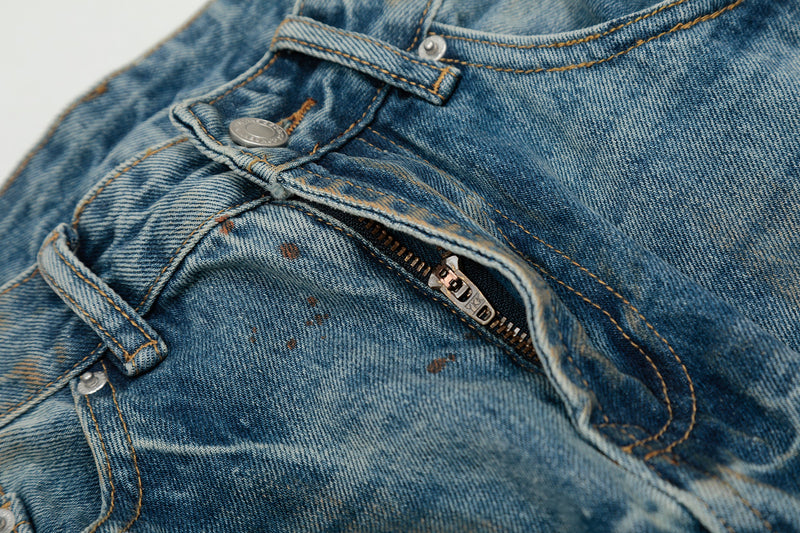 Close-up of front waistband and zipper fly on distressed blue jeans with metal button