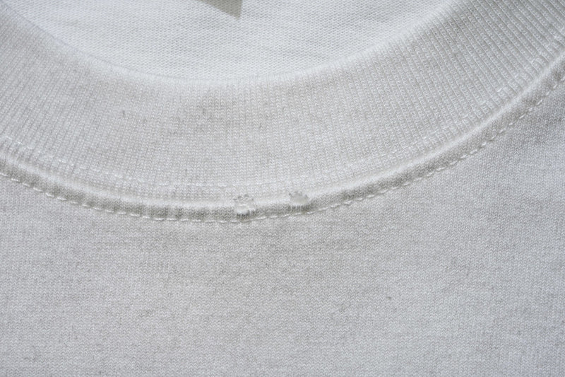 Close-up of a white ribbed crewneck T-shirt collar and stitching detail in soft cotton fabric