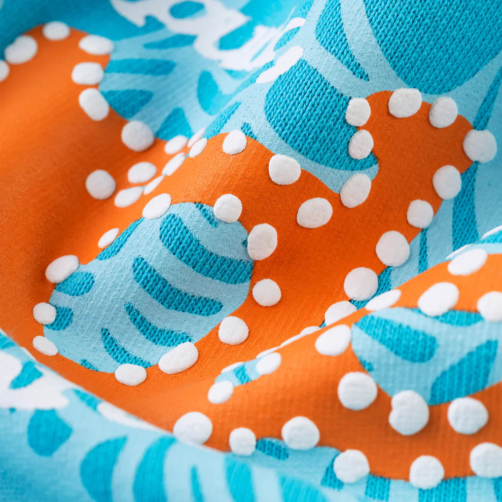 Close-up of bold, colorful fabric with orange and blue shapes and raised white dots, evoking streetwear vibes like the Sp5der “Nevermind the Spider” Hoodie – Sky Blue 440GSM Heavyweight Streetwear Pullover.
