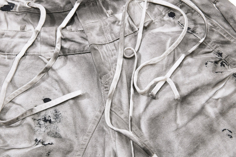 Close-up of front waistband and drawstrings on gray splatter-wash jeans