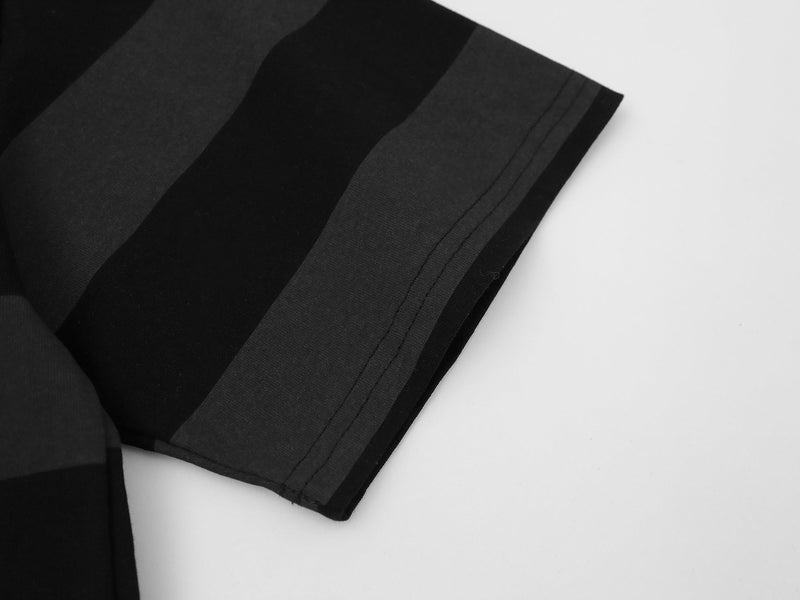 Close-up of a black oversized striped graphic tee sleeve with stitched hem on a white background