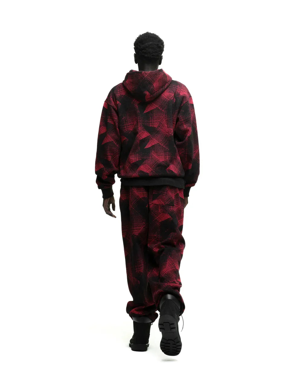 A person with short curly hair, seen from behind, wears the Red and Black Graphic Hoodie with Star Detail and Spider Web Print – Comfort Fit Pullover Hoodie, paired with matching pants, walking against a white background.