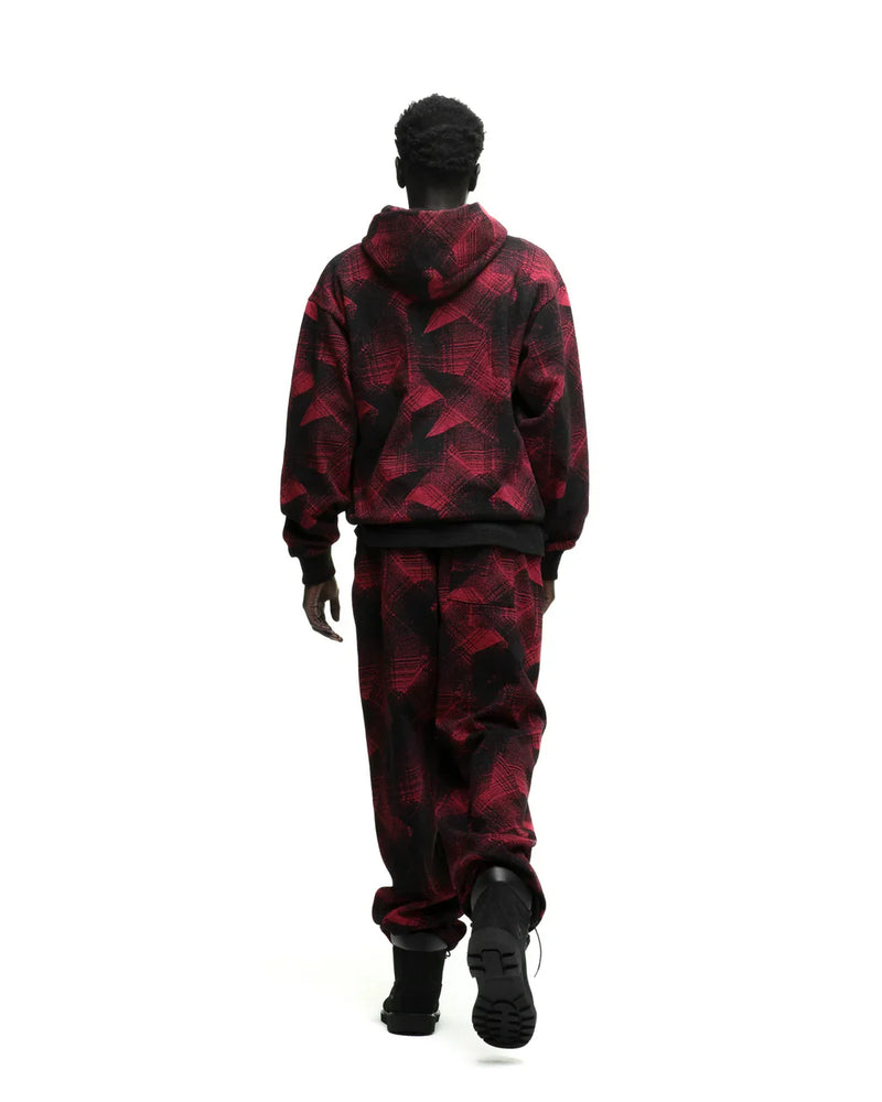 A person with short curly hair, seen from behind, wears the Red and Black Graphic Hoodie with Star Detail and Spider Web Print – Comfort Fit Pullover Hoodie, paired with matching pants, walking against a white background.