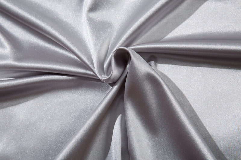 Close-up of shiny light gray jersey fabric gathered in folds