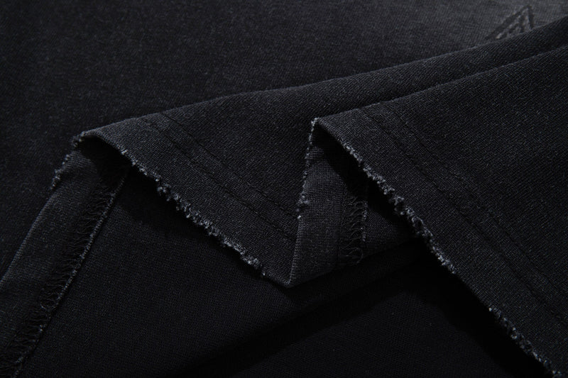 Close-up of a black washed graphic tee sleeve with raw hem and vintage distressed texture