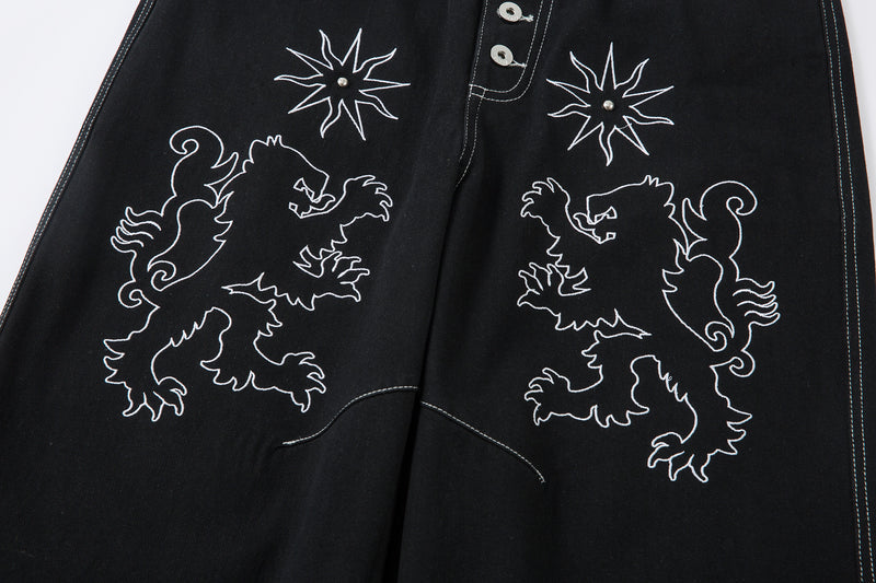 Front view of black jeans with mirrored lion embroidery and star motifs