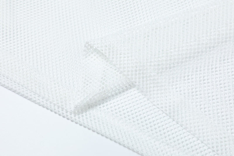 Close-up of white mesh jersey fabric with a lightweight perforated athletic texture and draped folds