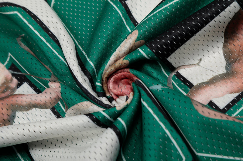 Close-up of green and white mesh football jersey fabric with black trim and angel graphic details