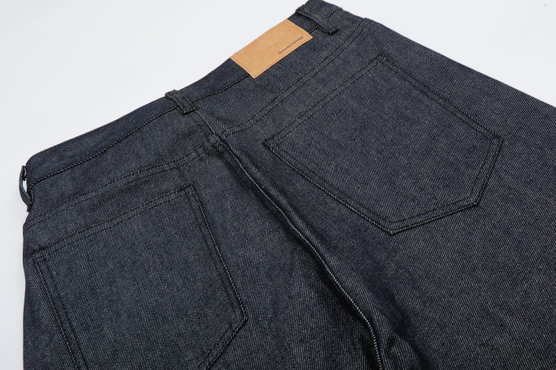 Close-up back view of dark wash denim jorts with waistband label and patch pockets