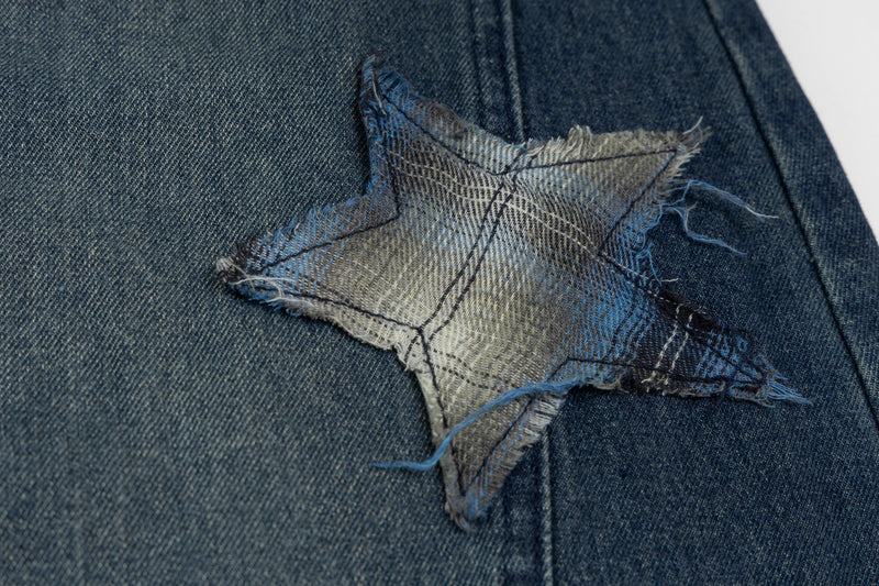 Close-up of star patch appliqué on dark blue denim with frayed edges