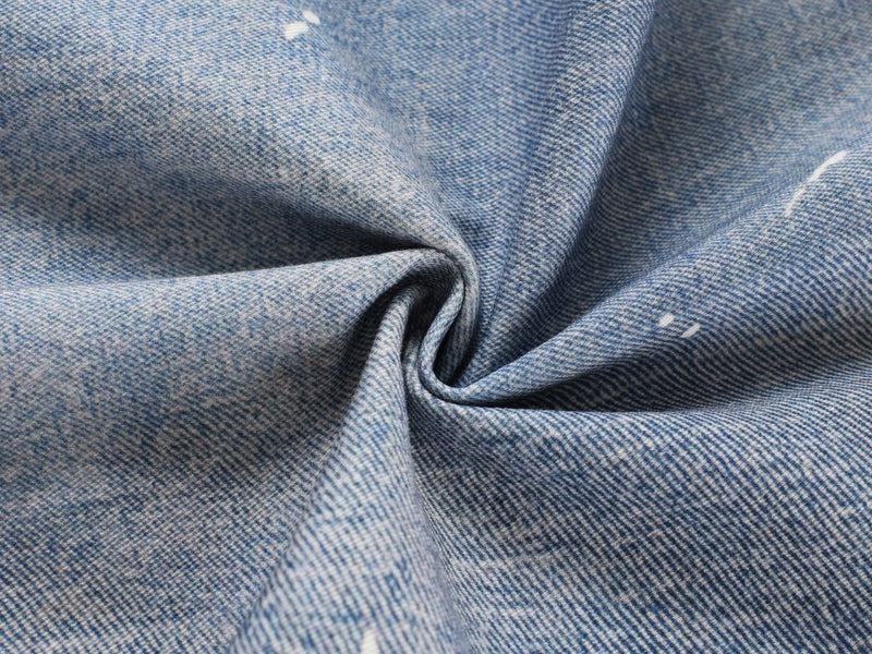 Close-up of blue denim fabric texture with slight twist and paint specks