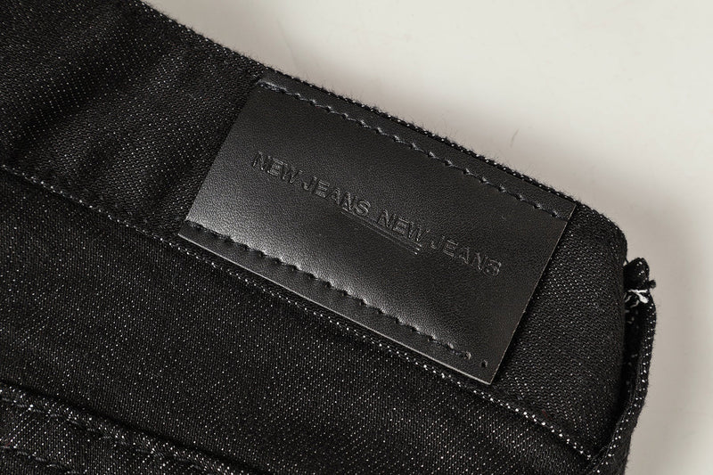 Black leather waistband label embossed with NEW JEANS NEW JEANS