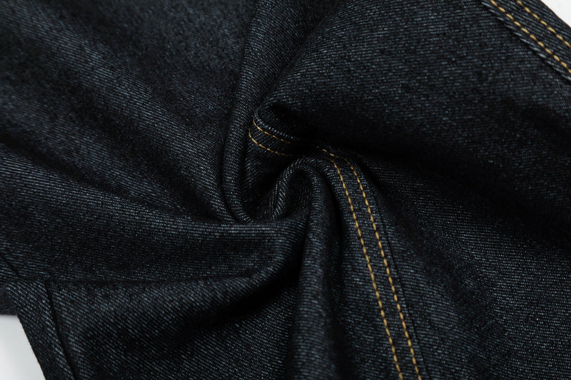 Close-up of black denim fabric fold with gold topstitching and textured weave