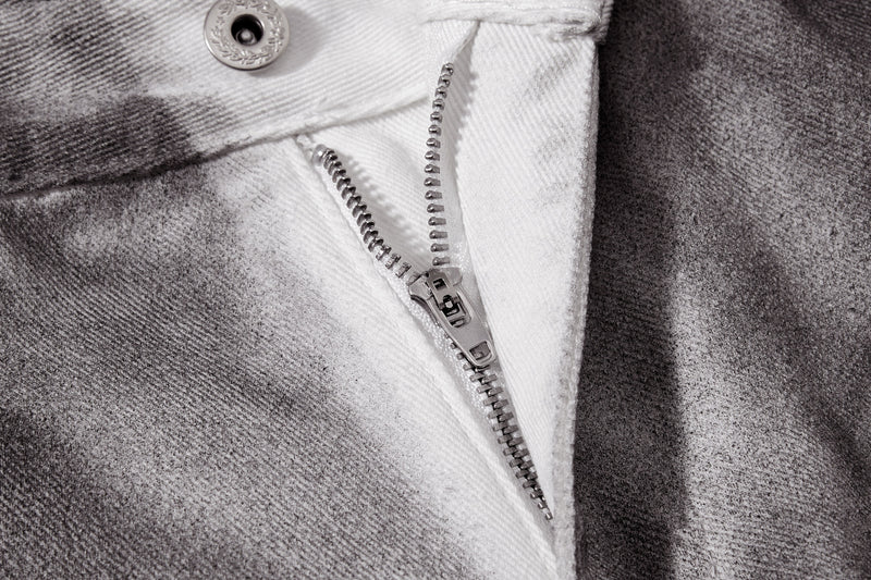 Close-up of zipper fly and button closure on gray washed denim pants