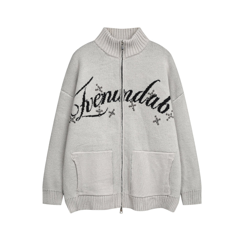 Light gray knit zip cardigan with black script lettering and studded eye graphic on the front