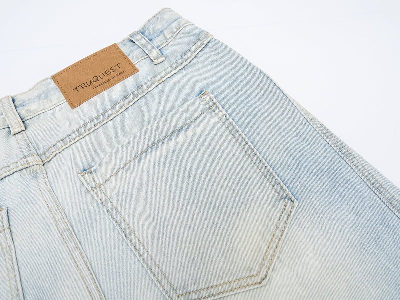Close-up of back pocket and tan logo patch on light wash denim jeans