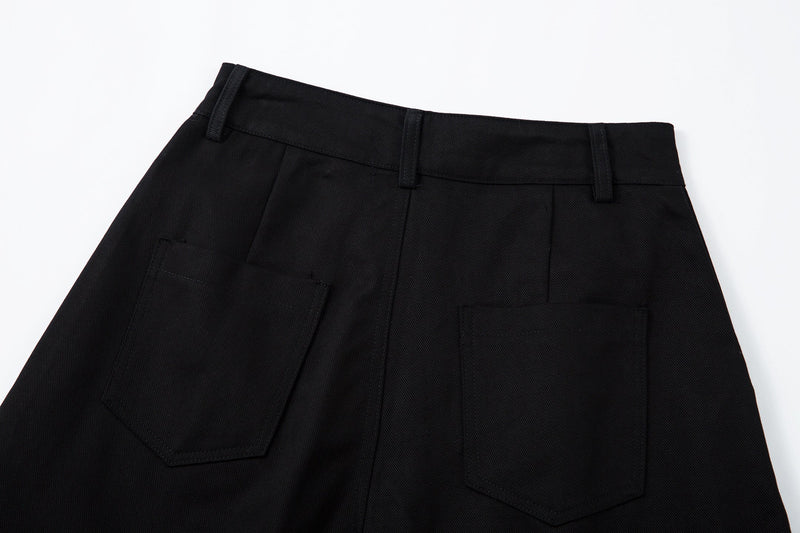 Close-up of the back waistband and patch pockets on black curved-leg pants