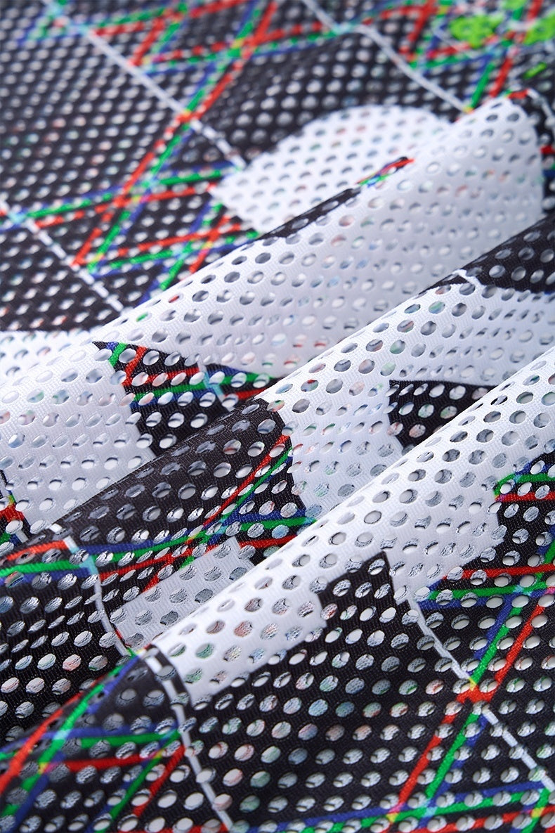 Close-up of perforated mesh jersey fabric with black, white and colorful geometric streetwear pattern