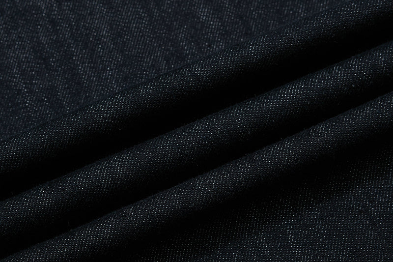 Close-up of dark wash denim fabric showing texture and diagonal folds