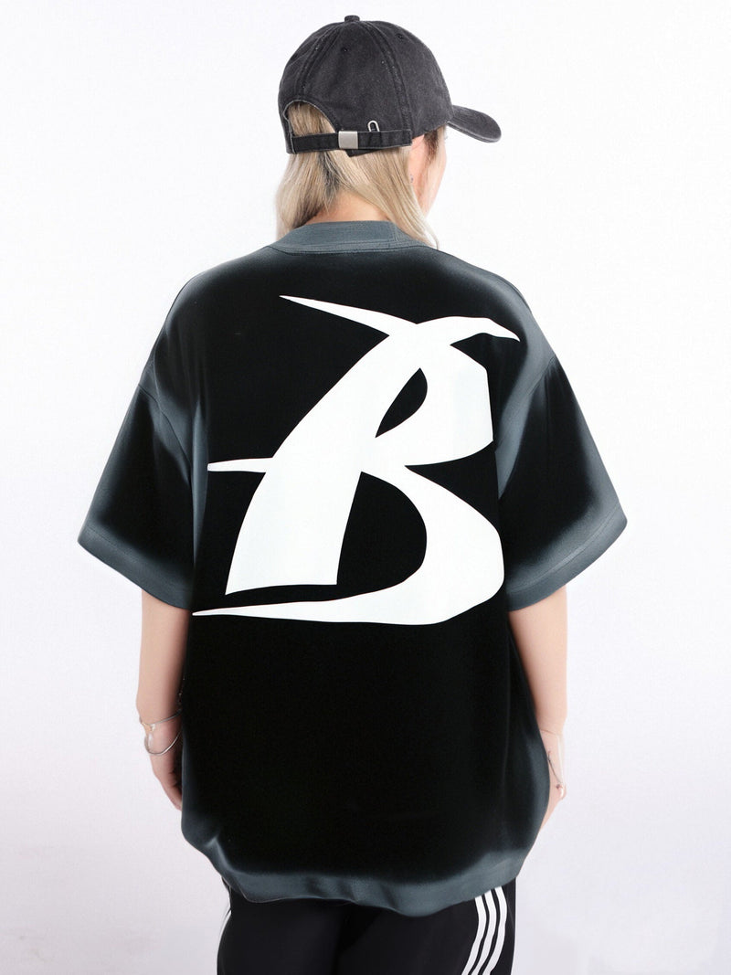 Black oversized streetwear tee with a large white graphic logo on the back, worn with a black cap