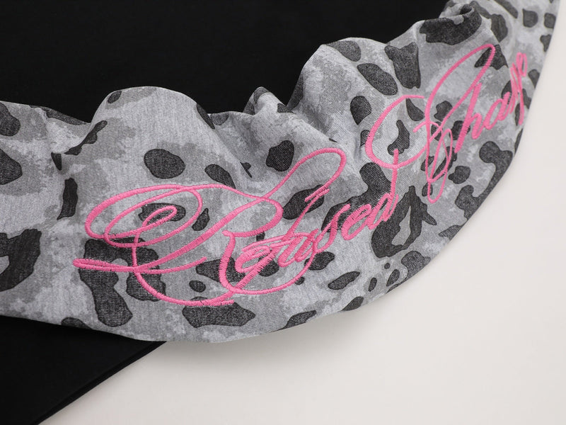 Close-up of pink script embroidery on gray leopard-print sleeve