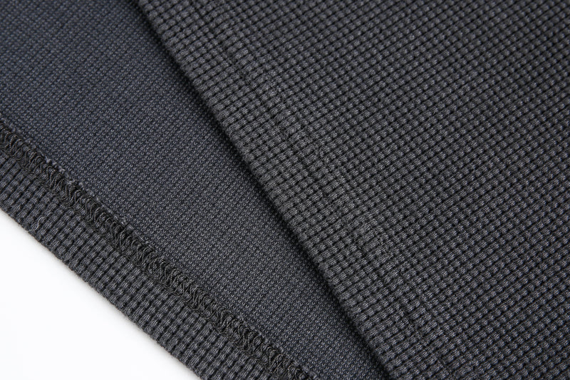 Close-up of black waffle knit sleeve cuff and hem stitching