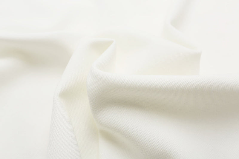 Close-up of white textured polo shirt fabric with soft folds and clean military-inspired styling