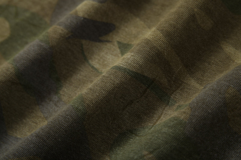 Close-up of camo fabric texture with soft folds and muted green and brown pattern