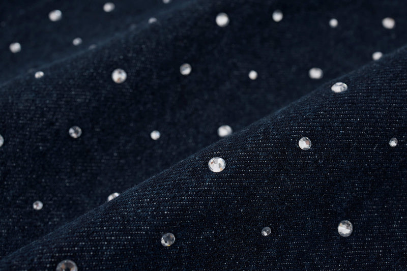 Macro close-up of black denim fabric with clear crystal studs