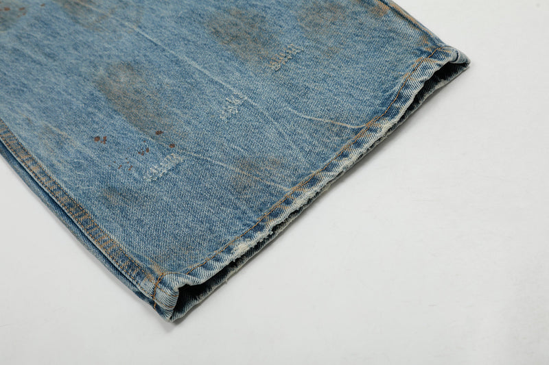 Close-up of hemmed jean leg with faded wash, light distressing, and raw edge detail
