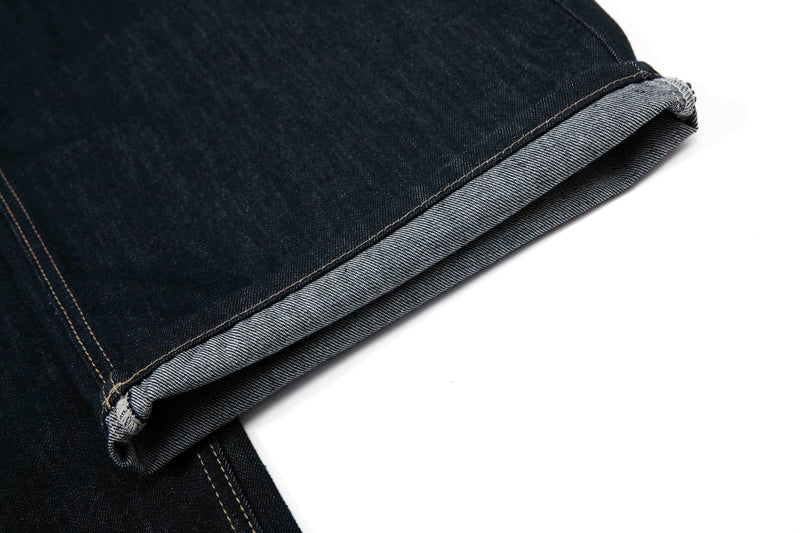 Folded hem of dark wash denim pants showing lighter inner denim and stitched cuff