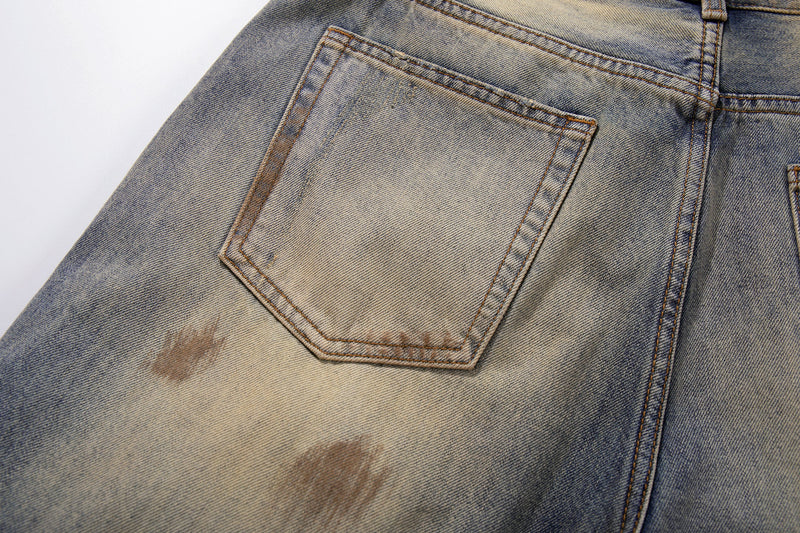 Close-up of back pocket on light faded denim with brown distress marks