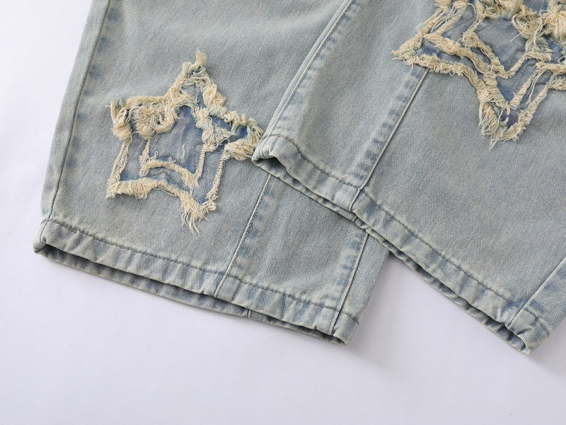 Hem close-up of wide-leg light wash jeans with frayed star patches